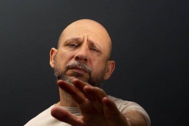 50 'li yaşlarında, stres ya da acı jesti gösteren duygusal olarak sarsılmış bir adam. Zayıf ya da depresif hissediyorum. Koyu arkaplanda izole.