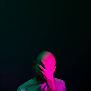 Baş ağrısı ya da migrenden muzdarip üzgün bir adam. Yüzünde acı dolu bir ifade olan stresli bir adam korkunç bir zayıflık ya da depresyon hissediyor. Koyu arkaplanda izole.