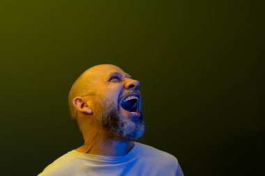 Sakallı, mutlu ve kel bir adam. Öylesine gülümsüyor ve yukarı bakıyor. Koyu yeşil arka planda izole edilmiş.