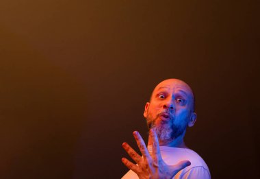 Komik el hareketleri yapan mutlu kel adam. Güç, başarı ve başarı kavramı. Koyu kırmızı arkaplanda izole.