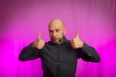 Sakallı ve kel bir adamın portresi. Ellerle tabela yapıyor. Pembe arka planda izole edilmiş.