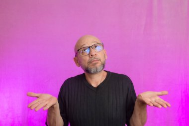 Sakallı ve kel bir adamın portresi. Ellerle tabela yapıyor. Pembe arka planda izole edilmiş.