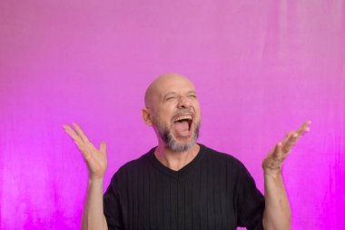 Sakallı ve kel adam elleriyle çeşitli işaretler yapıyor. Pembe arka planda izole edilmiş.