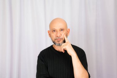 Sakallı ve kel adam elleriyle çeşitli işaretler yapıyor. Gri arkaplanda izole edilmiş.