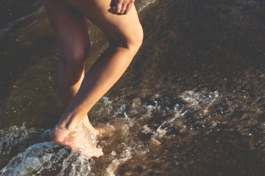 Sahilde suda yürüyen bir kadının bacaklarının bir parçası. Guaibim, Valenca, Bahia.