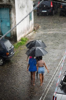 Valenca, Bahia, Brezilya - 24 Aralık 2022: Valenca, Bahia 'da insanlar şemsiyeyle sokakta yürüyor.
