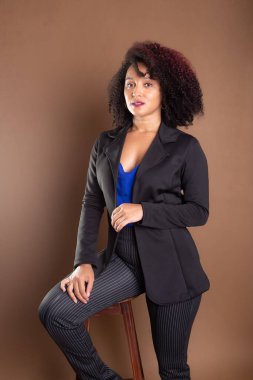 Genç yönetici, zarif ve güzel, tahta bir tabureye yaslanıyor. Başarı konsepti.