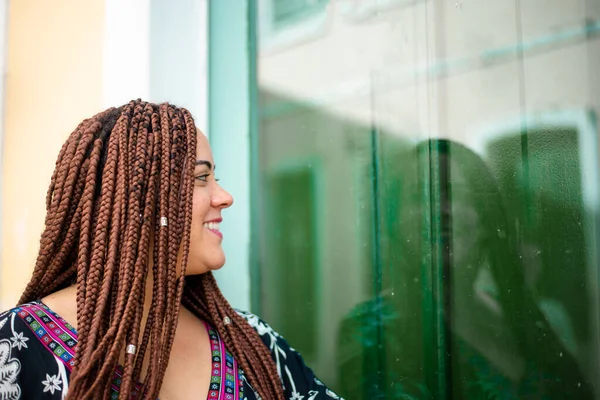 stock image Portrait of a beautiful woman standing by a green mirrored door, happy and smiling. Tourist on trip. Pelourinho, Brazil.