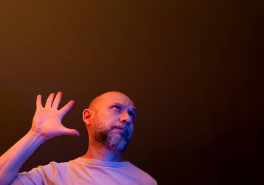 Komik el hareketleri yapan mutlu kel adam. Güç, başarı ve başarı kavramı. Koyu kırmızı arkaplanda izole.