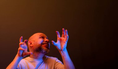 Komik el hareketleri yapan mutlu kel adam. Güç, başarı ve başarı kavramı. Koyu kırmızı arkaplanda izole.