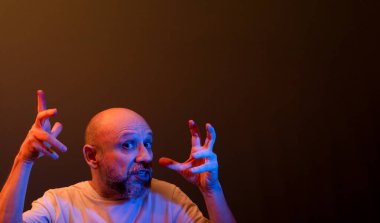 Komik el hareketleri yapan mutlu kel adam. Güç, başarı ve başarı kavramı. Koyu kırmızı arkaplanda izole.