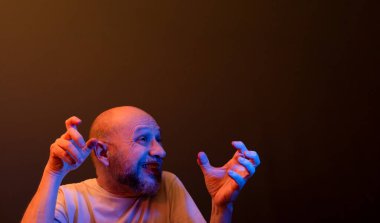 Komik el hareketleri yapan mutlu kel adam. Güç, başarı ve başarı kavramı. Koyu kırmızı arkaplanda izole.