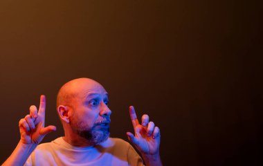 Komik el hareketleri yapan mutlu kel adam. Güç, başarı ve başarı kavramı. Koyu kırmızı arkaplanda izole.