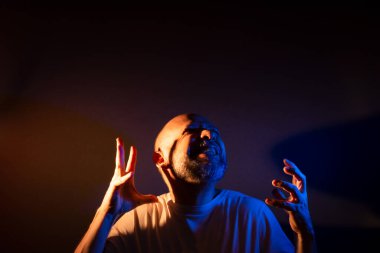 Komik sakallı kel adam farklı ifadeler ve jestler yapıyor. Mutlu, çok gülümsüyor. Koyu kırmızı arkaplanda izole.