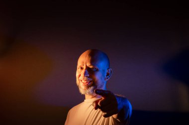 Komik sakallı kel adam farklı ifadeler ve jestler yapıyor. Mutlu, çok gülümsüyor. Koyu kırmızı arkaplanda izole.