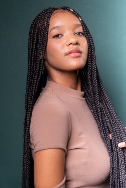 Uzun örgülü saçlı, güzel siyah bir mankenin portresi. Koyu renkli arkaplanda izole edilmiş.