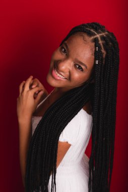 Beyaz giysili güzel siyah kadın kameraya bakıyor. Kırmızı arkaplanda izole.