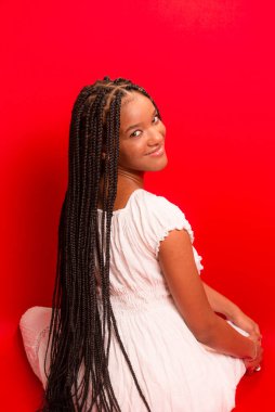 Güzel siyah kadın kameraya gülümsüyor. Kırmızı arkaplanda izole