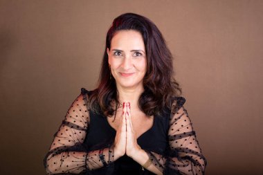 Koçluk yapan kadının portresi, mutlu, dua eden ellerle. Motivasyon ve demokratik yönetim. Kahverengi arkaplanda izole.