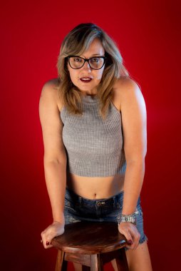 Kameraya poz veren güzel, beyaz, olgun bir kadın. Pozitif kişi. Kırmızı arkaplanda izole.