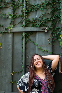 Yeşil bitkileri olan yeşil bir kapıya karşı mutlu mesut ayakta duran güzel bir kadın. Seyahatte bir turist. Pelourinho, Brezilya.