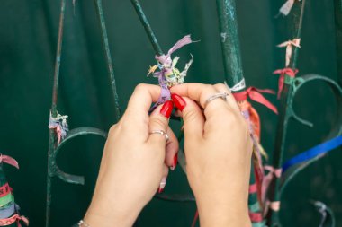 Yeşil demir korkuluklara kurdele bağlayan bir kadının elleri yakın plan. Pelourinho, Brezilya.