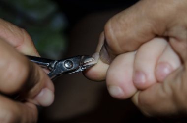 Yetişkin eller, bir çocuğun ayak tırnaklarını kesmek için çelik makas kullanıyor. bakım ve hijyen kavramı.
