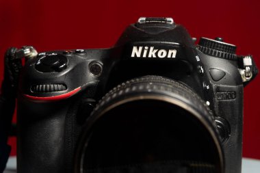 Salvador, Bahia, Brezilya - 30 Temmuz 2023: Nikon D7100 tarafından çekilen profesyonel bir DSLR kamerasının yakın plan portresi, Nikkor 16-85 mm f / 3.5 mercek kırmızı zemin üzerinde izole edildi.