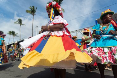 Salvador, Bahia, Brezilya - 11 Şubat 2023: Fuzue, Bahia, Brezilya 'daki karnaval öncesi Fuzue sırasında eteklerini kıvırarak karakter yürüyüşü yapan kadınlar.
