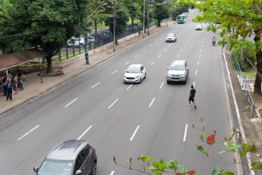 Salvador, Bahia, Brazil - August 11, 2023: Pedestrian is seen risking his life crossing the busy lanes of Avenida Tancredo Neves in Salvador, Bahia, clipart