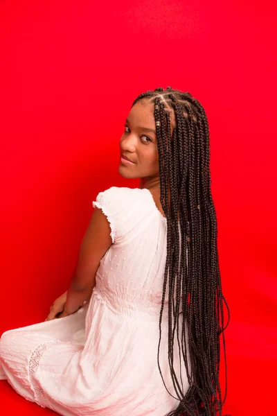 Güzel siyah kadın kameraya gülümsüyor. Kırmızı arkaplanda izole