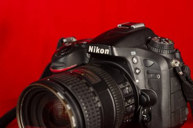 Salvador, Bahia, Brezilya - 30 Temmuz 2023: Nikon 'un profesyonel bir DSLR kamerasının yakın plan portresi, model D7100, kırmızı zemin üzerinde izole edilmiş