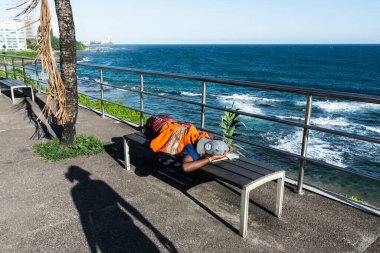 Salvador, Bahia, Brezilya - 22 Ekim 2022: Salvador, Bahia 'da plajın kenarında uyuyan evsiz adam.