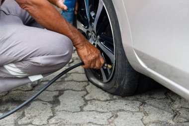 Salvador, Bahia, Brezilya - 11 Ağustos 2023: Bir benzin istasyonunda çalışan bir işçi, Salvador, Bahia 'da Avenida Tancredo Neves' de bir araba lastiği şişirdiği görüldü.