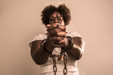 Yüzünde eski paslı zincirler ve maskeyle kapana kısılmış üzgün kadın portresi. Dua eden eller yardım istiyor. Köle ticareti önleme kavramı.
