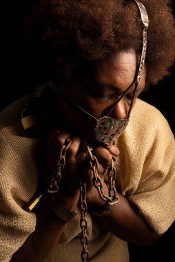 Ellerinde zincirler ve yüzünde demir bir maske olan siyah bir kadının yakın plan portresi. Köle Anastacia. Brezilya 'da kölelik.