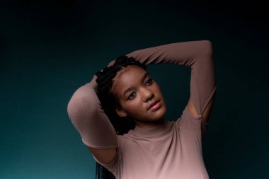 Uzun örgülü saçlı, güzel siyah bir mankenin portresi. Koyu renkli arkaplanda izole edilmiş.