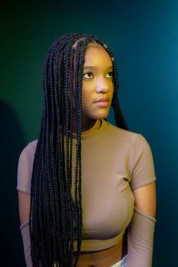 Örgülü genç bir kadın, ciddi. Koyu renkli arkaplanda izole edilmiş.