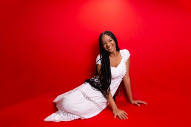 Güzel siyah kadın kameraya gülümsüyor. Kırmızı arkaplanda izole