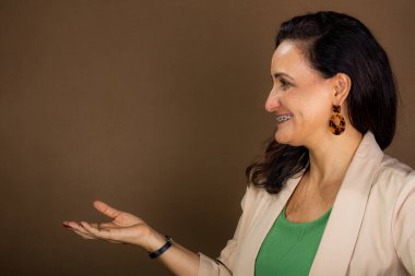 Gülümseyen portre ve kendine güvenen koçluk yapan kadın el hareketi yapıyor. Motivasyon ve demokratik yönetim. Kahverengi arkaplanda izole.
