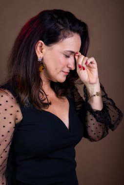 Koçluk yapan bir kadının portresi, ciddi, eli yüzü ve gözleri kapalı. Motivasyon yönetimi. Kahverengi arkaplanda izole.