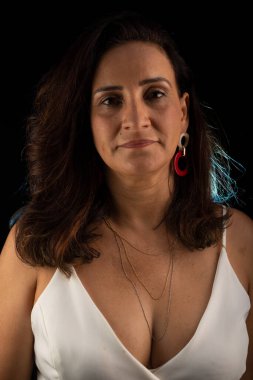 Yetişkin bir kadının stüdyo portresi, beyaz kıyafetler giymiş, kameraya bakıyor. Siyah arkaplanda izole.