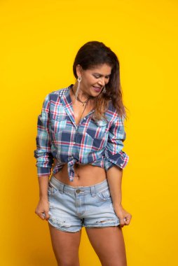 Haziran karakteri gibi giyinmiş güzel olgun bir kadın Forro dansı yapıyor. Sao Joao partisi. Sarı arkaplanda izole edilmiş.