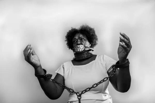 Portrait of a black woman in chains with an iron mask over her mouth. Slavery in Brazil. Studio reproduction.