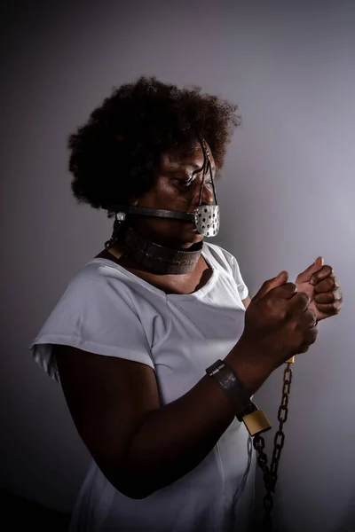 Portrait of a black woman with chains around her body and an iron mask over her mouth. Slavery in Brazil. Slave Anastacia.