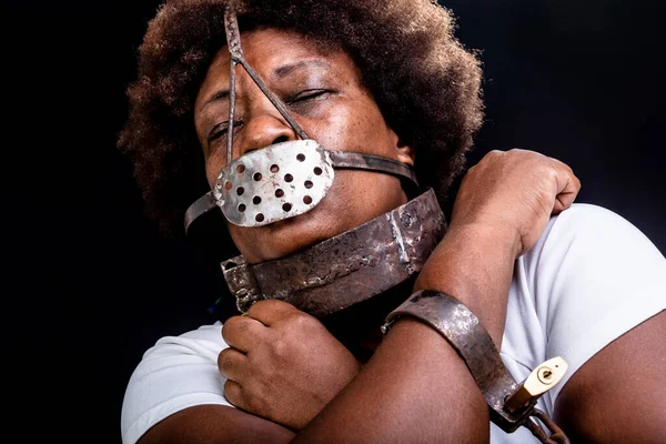 Black woman in chains with an iron mask on her face, representing the slave Anastacia. Pain and suffering, torture. Slavery in Brazil.