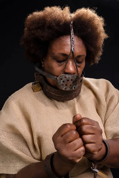 Black woman in chains with an iron mask on her face, representing the slave Anastacia. sadness and apathy, pain. Slavery in Brazil.
