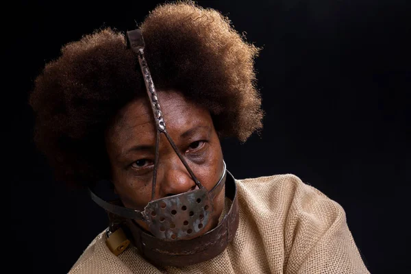 Black woman in chains with an iron mask on her face, representing the slave Anastacia. sadness and apathy, pain. Slavery in Brazil.