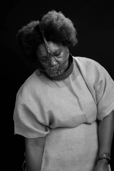Black woman, standing, chained and with an iron mask on her face representing the slave Anastacia. Slavery in Brazil. Isolated on black background.