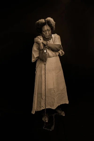 Black woman, standing, chained and with an iron mask on her face representing the slave Anastacia. Slavery in Brazil. Isolated on black background.